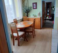 Jídelní kout v 2-pokojovém bytě s podlahou s dřevěným dekorem a světlým nábytkem.