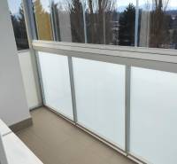 Zasklený balkon v 2-pokojovém bytě s výhledem na stromy a hory.