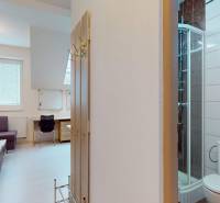 Kanceláře s rohovou sedačkou, stolem, sprchou a dřevěným dekorem na stěně.