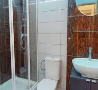 Koupelna s moderní sprchou, umyvadlem na skříňce a toaletou v kancelářích.