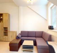 Na fotografii kanceláře dominuje fialová sedačka a světlé dřevěné dekorace.