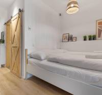 Ložnice v 1-pokojovém bytě s posuvnými dveřmi a podlahou s dřevěným dekorem.