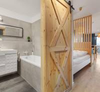 Interiér 1-pokojového bytu s vanou a podlahou s dřevěným dekorem.