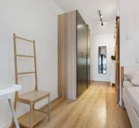 Interiér 1-pokojového bytu s podlahou s dřevěným dekorem, skříní a postelí.