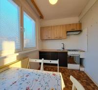 Kuchyně v 2pokojovém bytě s podlahou s dřevěným dekorem a jídelním stolem.