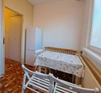 Jídelna v 2-pokojovém bytě s podlahou s dřevěným dekorem a bílou lednicí.