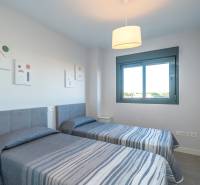 Dvě jednolůžkové postele v 2-pokojovém bytě s oknem a dekorativními obrazy na stěně.