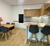 Kuchyně v 2-pokojovém bytě s podlahou s dřevěným dekorem, jídelním stolem a barovým pultem.