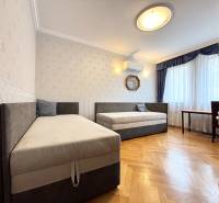 Pokoj ve 4pokojovém bytě s dvěma lůžky, klimatizací a podlahou s dřevěným dekorem.