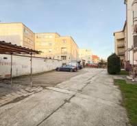 Parkoviště u 2pokojových bytů na Hodžově ulici v Trenčíně s auty a zelení.