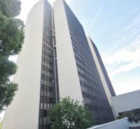 Výšková budova kanceláří na Kutlíkově ulici v Bratislavě - Lúky, částečně obklopená zelení.