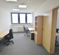 Kanceláře s kancelářským nábytkem, šedým kobercem a světlou stěnou, připravené k práci.