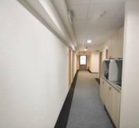 Kanceláře s úzkou chodbou a kobercem, světlé stěny a světlá Kutlíkova ulice v Bratislavě.