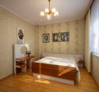 Ložnice v rodinném domě s podlahou s dřevěným dekorem a květinovými tapetami.