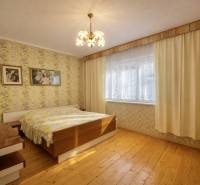 Ložnice v rodinném domě s tapetami, dřevěným dekorem a lustry.