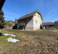 Rodinný dům v Terchové s velkým dvorem a přístřeškem, obklopený trávou a stromy.