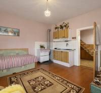 Pokoj s kuchyňskou linkou, pohovkou, sporákem a podlahou s dřevěným dekorem v rodinném domě.