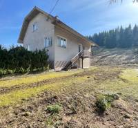 Rodinný dům v Terchové s velkým travnatým pozemkem, obklopený stromy.