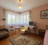 Obývací pokoj v rodinném domě s kobercem, televizorem a podlahou s dřevěným dekorem.