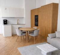 Kuchyně ve 3-pokojovém bytě s podlahou s dřevěným dekorem, šedým kobercem a jídelním stolem.