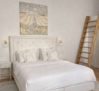 Světlá ložnice s postelí, obrazem na stěně, nočním stolkem a podlahou s dřevěným dekorem.