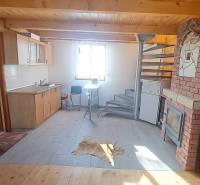 Chata s kuchyní, spirálovým schodištěm a podlahou s dřevěným dekorem.