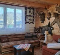 Interiér chaty s trofejemi, dřevěným obložením a podlahou s dřevěným dekorem.