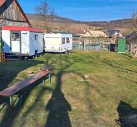 Stavební pozemek v Královcích Krnišově s míchačkou a přívěsnými vozíky na dvoře.