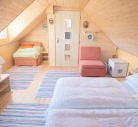 Dřevěný interiér chaty s podlahou s dřevěným dekorem, postelí a křeslem.