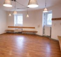 Obchodní prostory s podlahou s dřevěným dekorem, lavicemi a zavěšenými lampami.