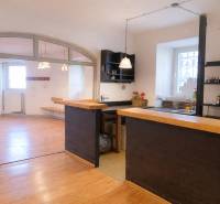 Obchodní prostory s barovým pultem a podlahou s dřevěným dekorem. Světlá místnost s okny.