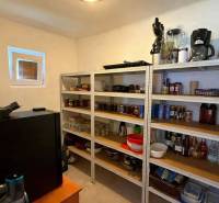 Spižírna v rodinném domě s policemi plnými zásob a kuchyňskými spotřebiči.