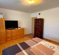 Pokoj v rodinném domě s televizí, skříní, kachlovými kamny a podlahou s dřevěným dekorem.