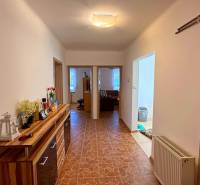 Chodba v rodinném domě s dlažbou a dřevěným dekorem skříňky.