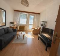 Obývací pokoj v 3-pokojovém bytě s podlahou s dřevěným dekorem a pohodlným nábytkem.