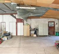 Interiér rodinného domu s rozlehlým prostorem, odloženými věcmi a cementovou podlahou.