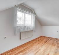 Pokoj v rodinném domě s oknem a podlahou s dřevěným dekorem.