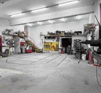 Dílna s nářadím a schody v rodinném domě. Stropy s osvětlením a betonová podlaha.