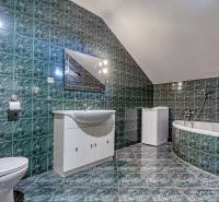 Koupelna v rodinném domě s vanou, zelenými kachličkami a bílým nábytkem.