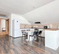 Kuchyně s jídelním stolem a spotřebiči v rodinném domě, podlaha s dřevěným dekorem.