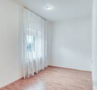 Světlá místnost s podlahou s dřevěným dekorem a záclonami v rodinném domě.