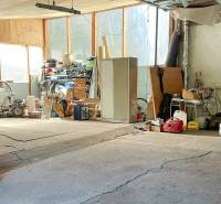 Garáž v rodinném domě plná nástrojů a strojů, s různým vybavením na policích.