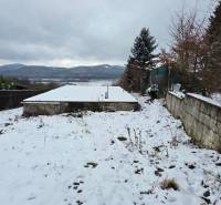 Sněhem pokryté rekreační pozemky v Považské Bystrici s výhledem na hory a zasazenými stromy.