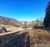 Krajina v obci Hronec, zemědělské a lesní pozemky s výhledem na hory a domy.