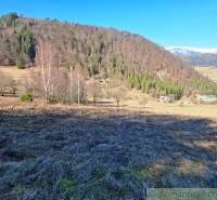 Pohled na Pozemky - bydlení v Hronci s lesy a horami v pozadí.