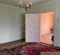 Pokoj v rodinném domě s kobercem, bílými dveřmi a lustry.