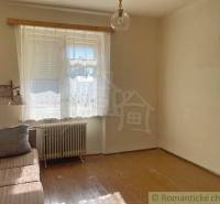 Pokoj v rodinném domě s pohovkou, oknem a podlahou s dřevěným dekorem.