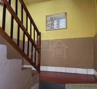 Schodiště s dřevěným zábradlím v rodinném domě se žlutými stěnami a obrazem.