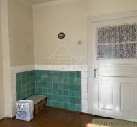 Interiér rodinného domu s bílými dveřmi a zeleno-bílými obkladačkami na stěnách.