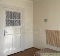 Interiér rodinného domu s bílými dveřmi, obkladem a podlahou s dřevěným dekorem.